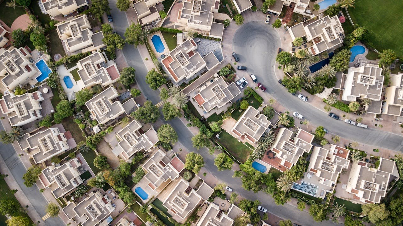 services-04 Explore a stunning aerial view of a residential area in Dubai with lush greenery and swimming pools.